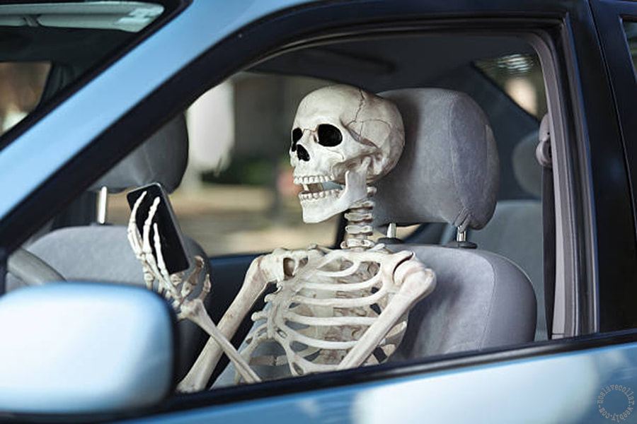 Skeleton holding a smartphone in a car