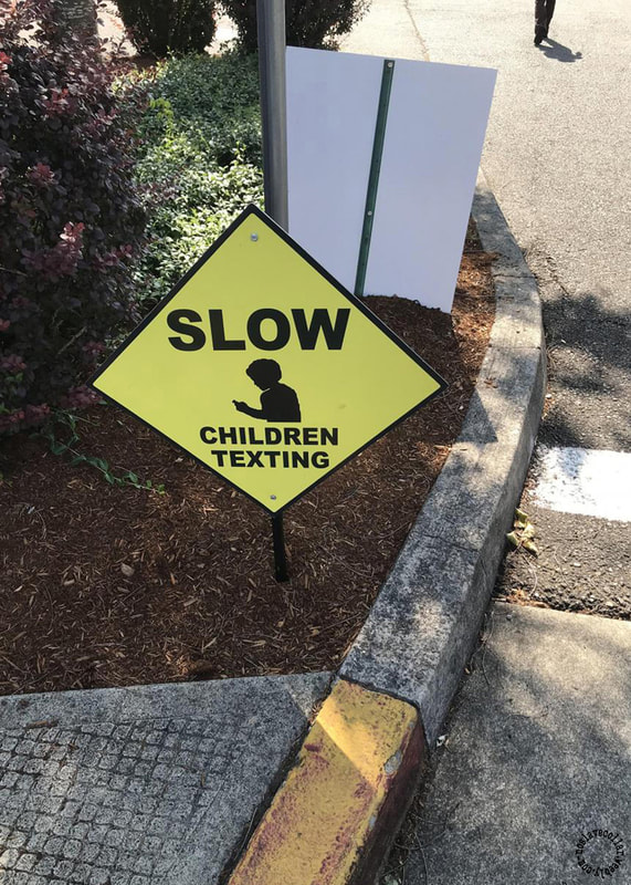 As seen at a crosswalk - 'Slow, Children texting' sign